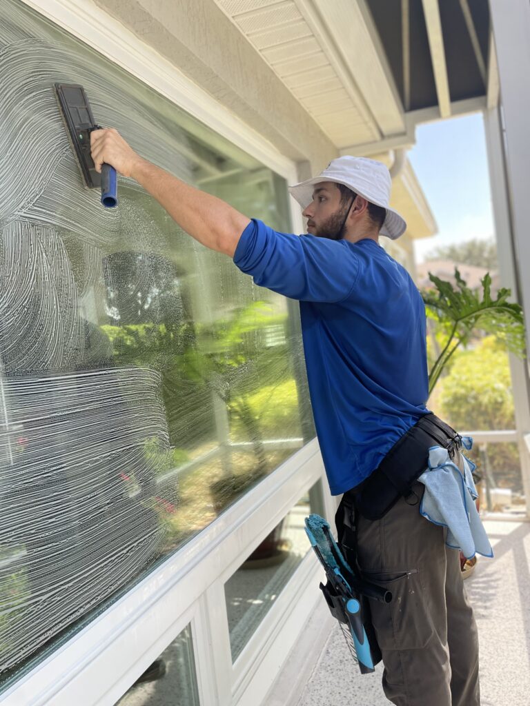 Technician cleaning exterior residential windows for a streak-free finish in The Villages, Florida
