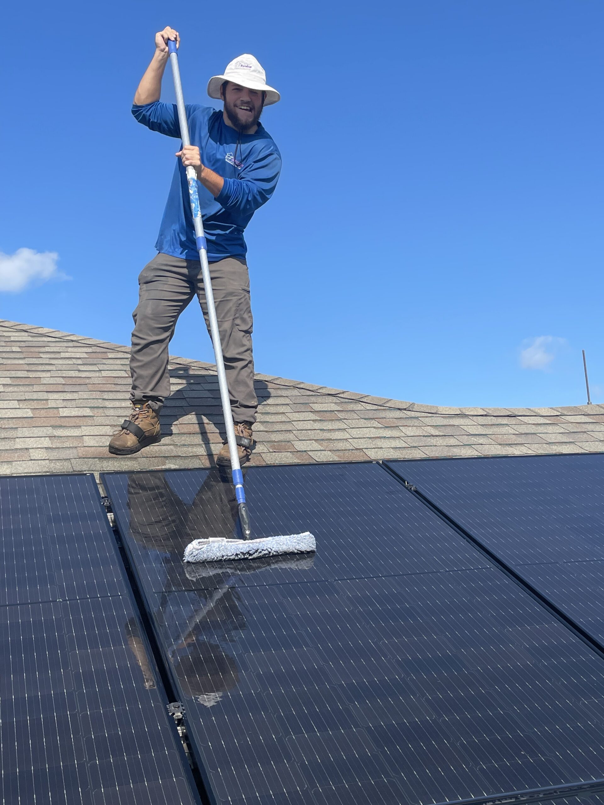 Technician cleaning rooftop solar panels in The Villages, FL using a professional water-fed pole system