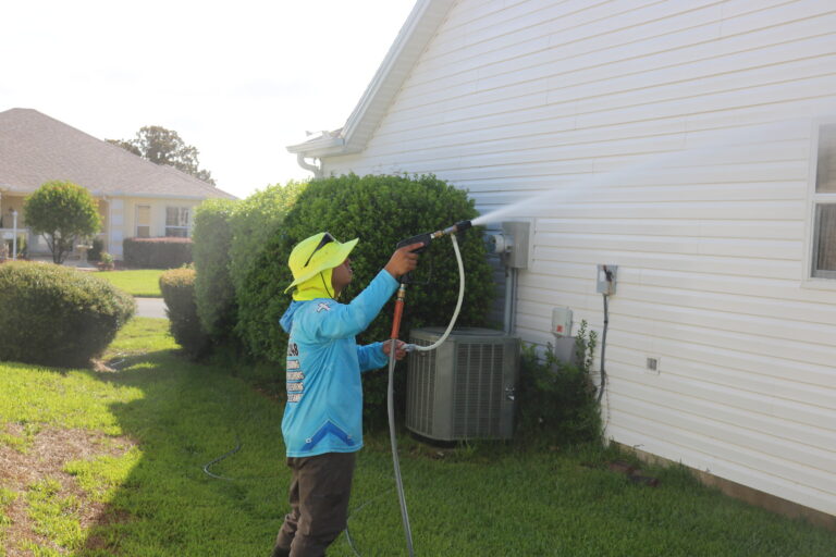C2 Services technician soft washing the siding of a single-story Florida home
