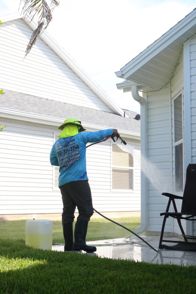 C2 Services technician soft washing white vinyl siding on a Florida home